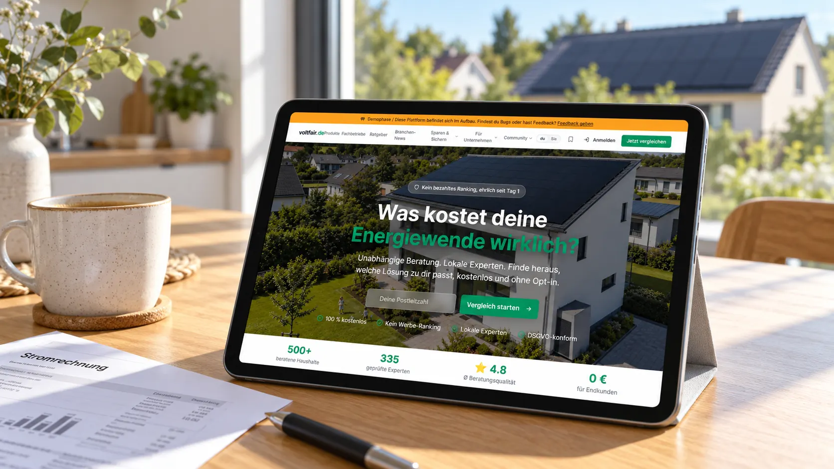 Tablet mit voltfair auf dem Küchentisch, im Fenster dahinter ein Dach mit Solarmodulen